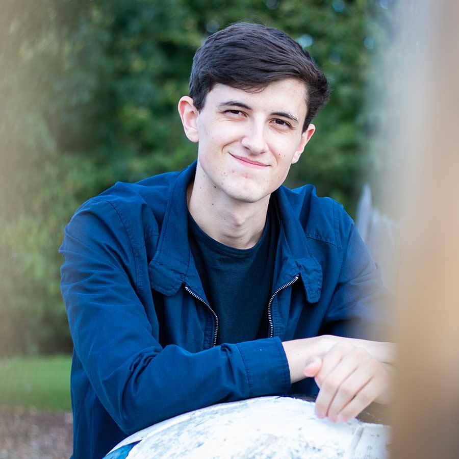 Male in a navy jacket leaning on a rock