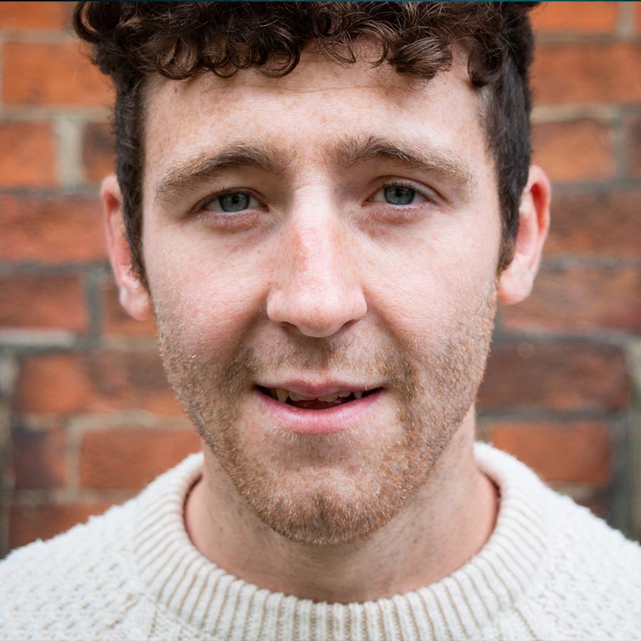 Male with dark curly hair in a cream knitted jumper