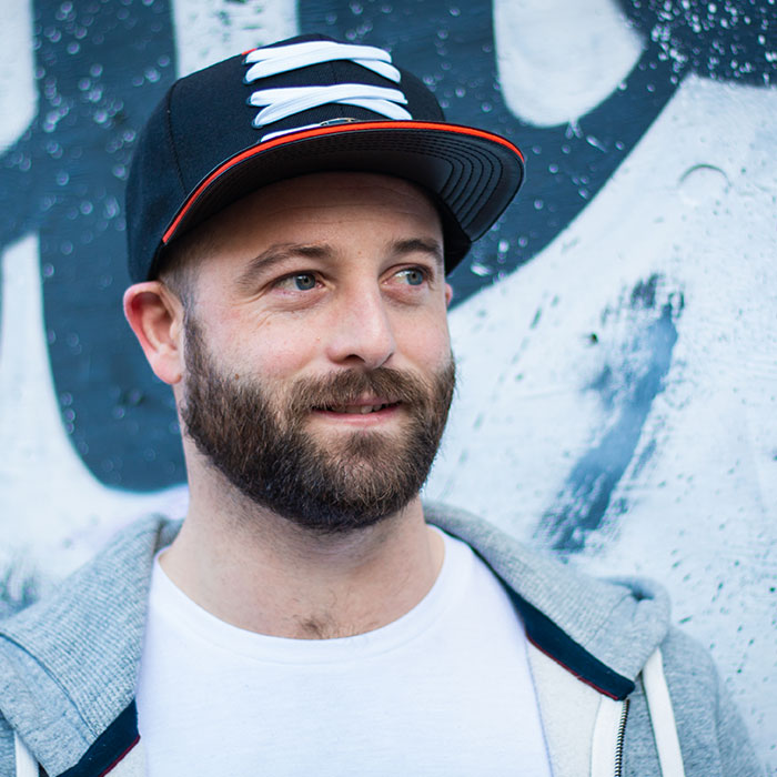 Male with beard and wearing a cap in front of a black and white arty wall - one of 20 dating photos