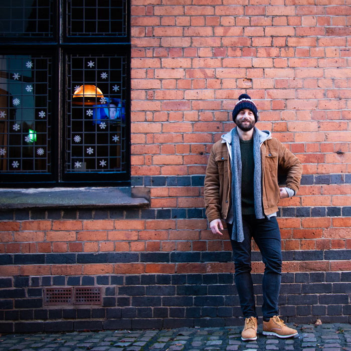 Male client stood against a brick wall outside The Castle pub, Nottingham during his dating photo shoot