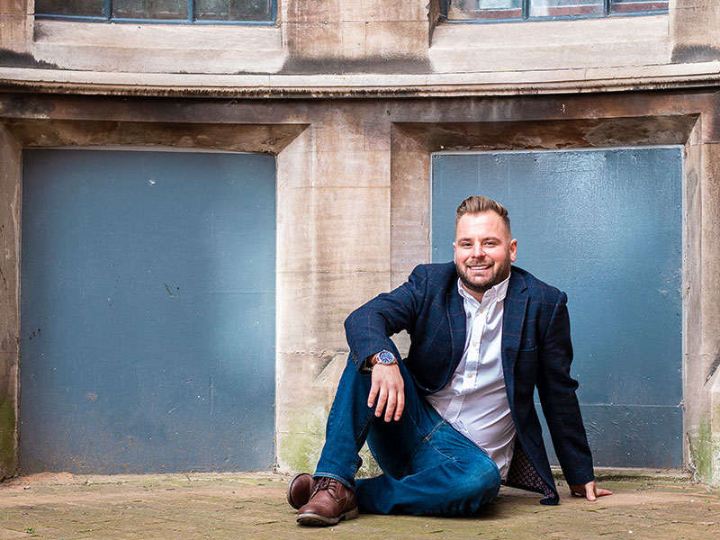 Male sitting on the floor for a photo during his dating photo shoot