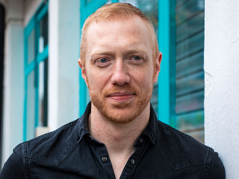 A male looking away from the camera in front of a bright backdrop