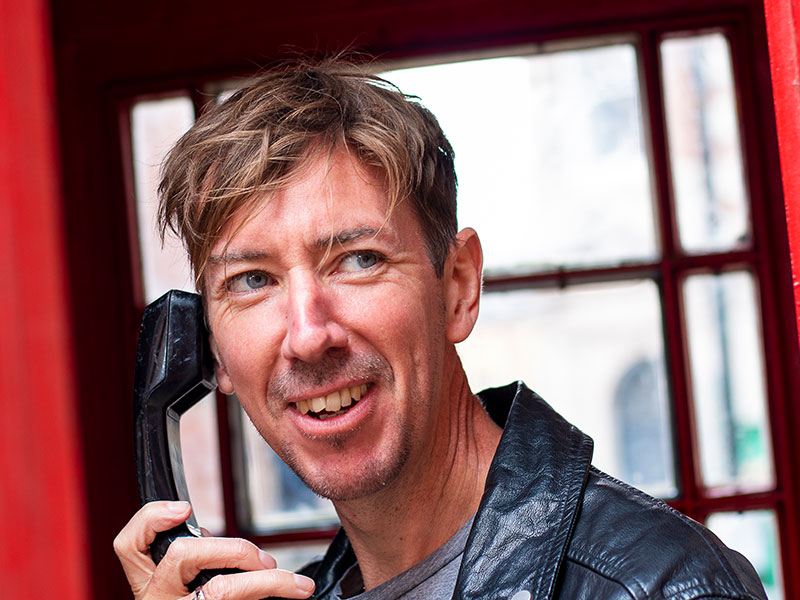 Male on the phone in a telephone box during his dating photo shoot