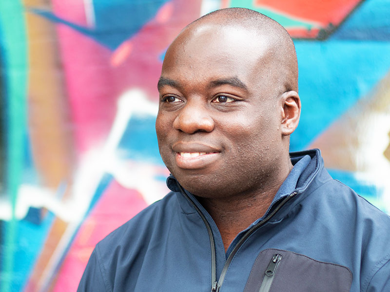 A man looking away from the camera against a graffiti wall