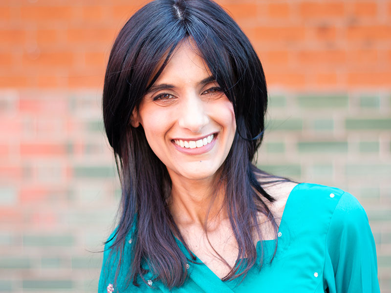 A woman smiling into the camera against a brick wall