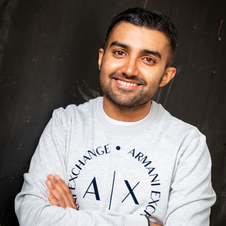 Male smiling with arms folded wearing branded jumper