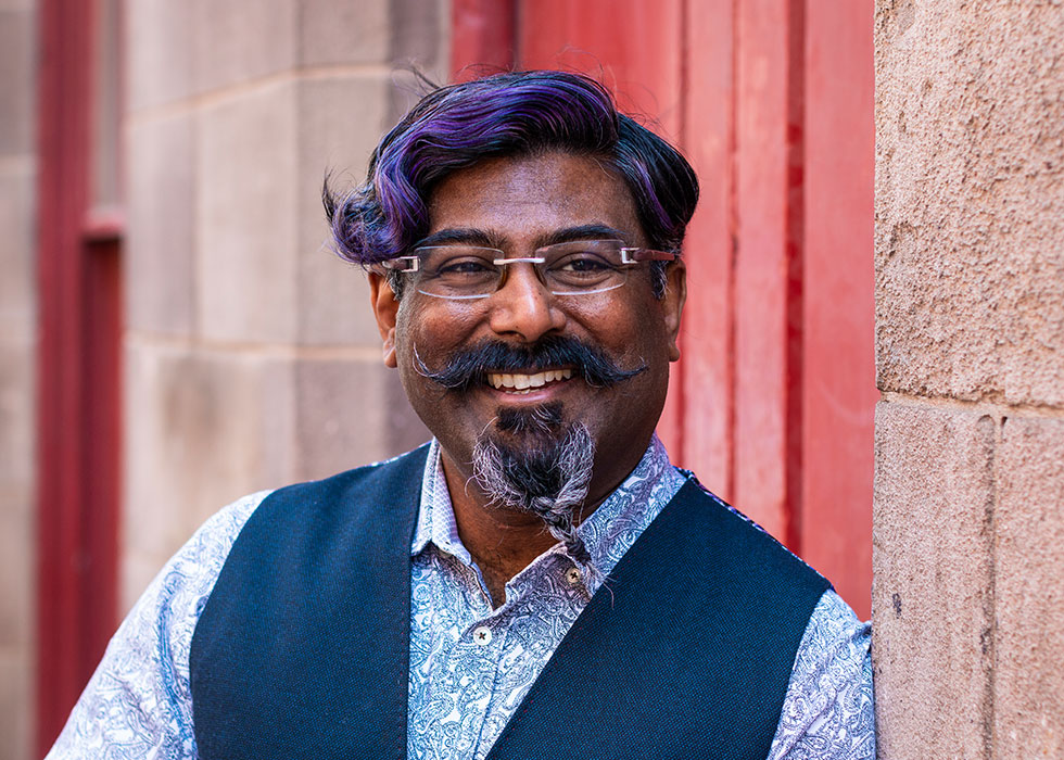 Photo of male single stood in front of a bright red door.